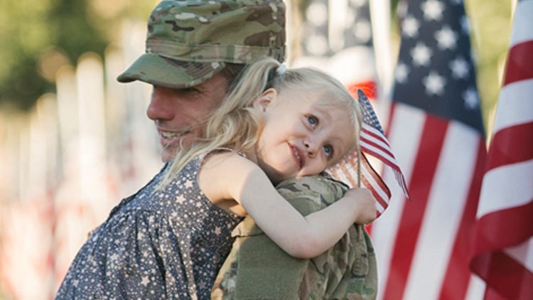 Military man in uniform holding little girl.