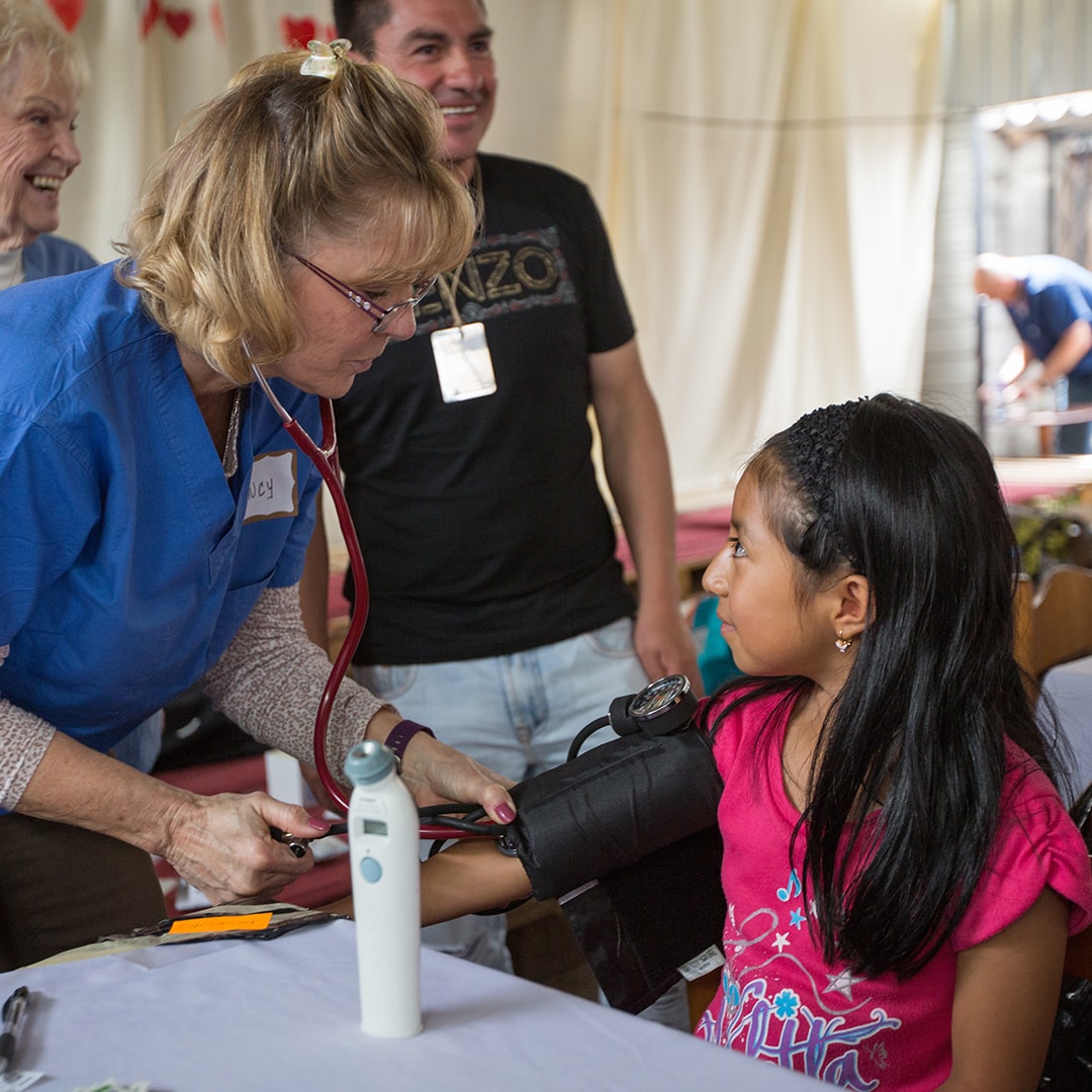 Nurse taking an Ecuadorian child's blood pressure.